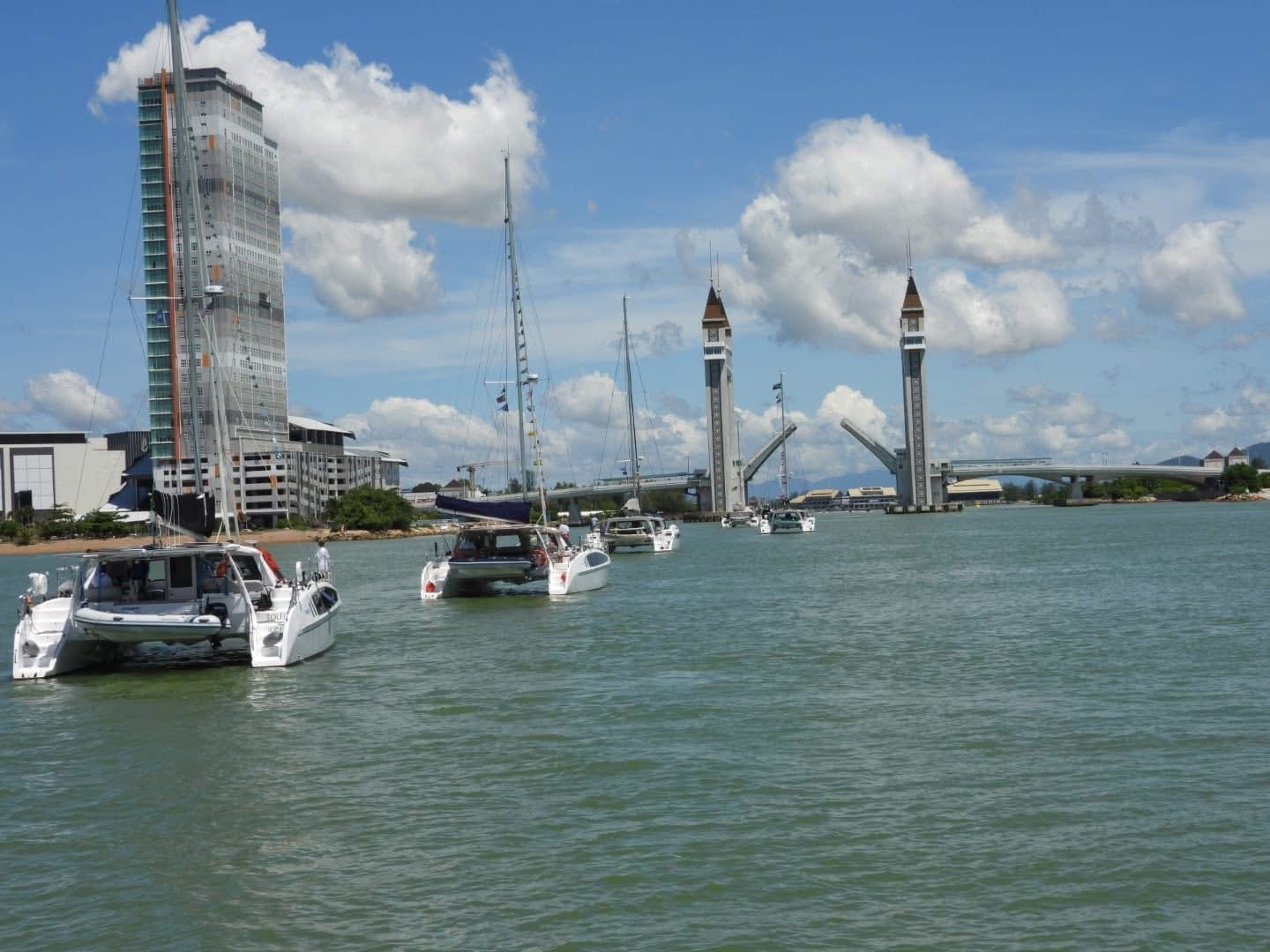Sailing catamarans approaching a marina entrance in Southeast Asia